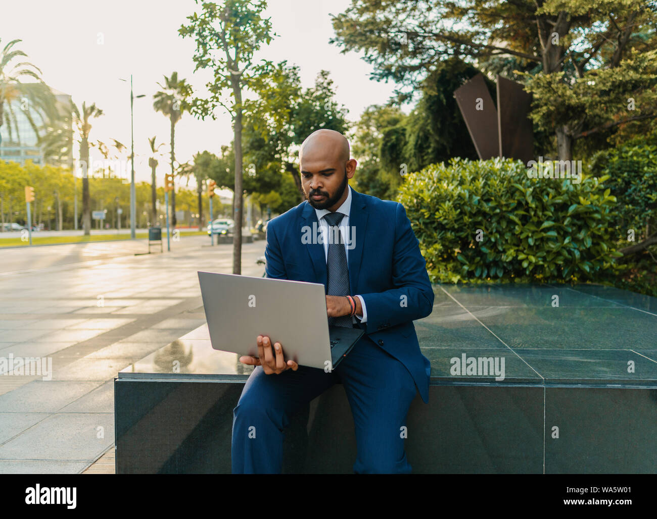 Commerciante indiano holding laptop notebook indossare tuta blu nei pressi di office Foto Stock