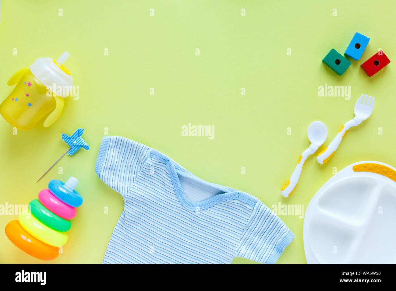 Baby Care sfondo accessori: bottiglia, a piramide e giocattoli su sfondo giallo con copia spazio; vista superiore, laici piatta Foto Stock