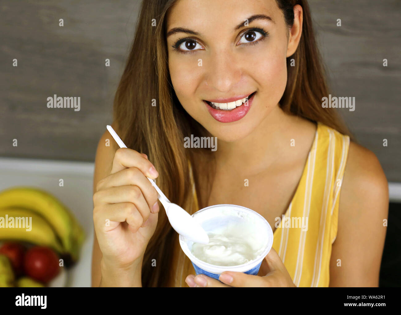 Ragazza luce mangiare lo yogurt a casa. Chiudere dall'alto. Un sano concetto. Foto Stock