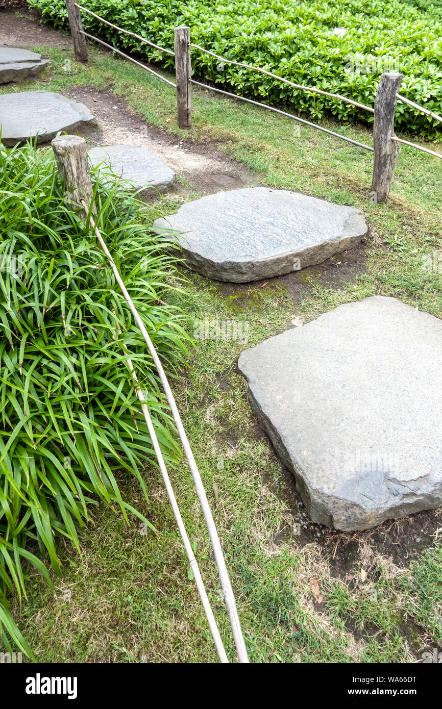 Giardino marciapiede, trampolini, erba ornamentale e recinzione di legno Foto Stock