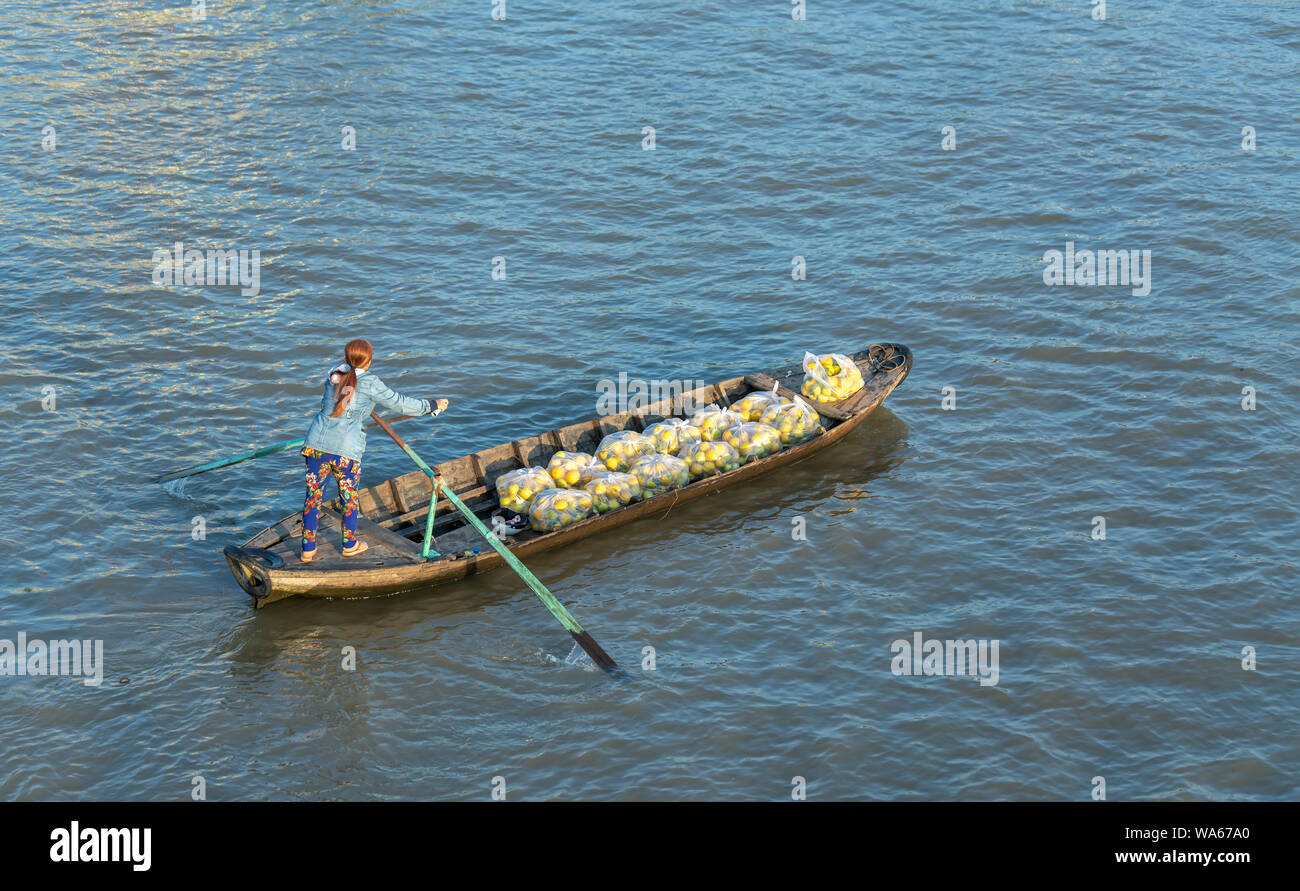 Traghetto di canottaggio donna porta i visitatori o i prodotti agricoli sul fiume mercato galleggiante , questo è il trasporto principale il nuovo anno lunare in Soc Trang, Foto Stock