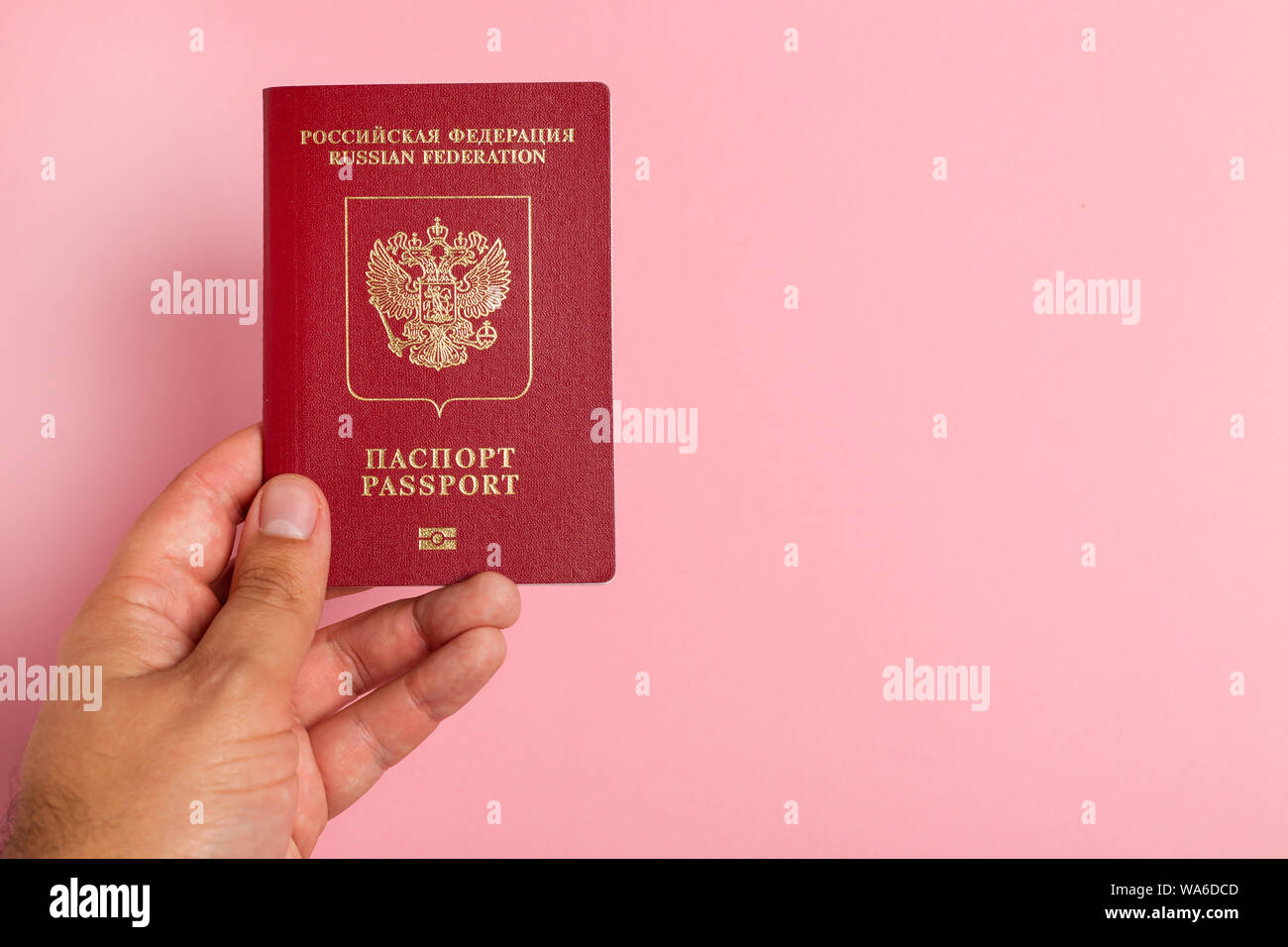 Russo passaporto internazionale in mano maschio su sfondo rosa Foto Stock