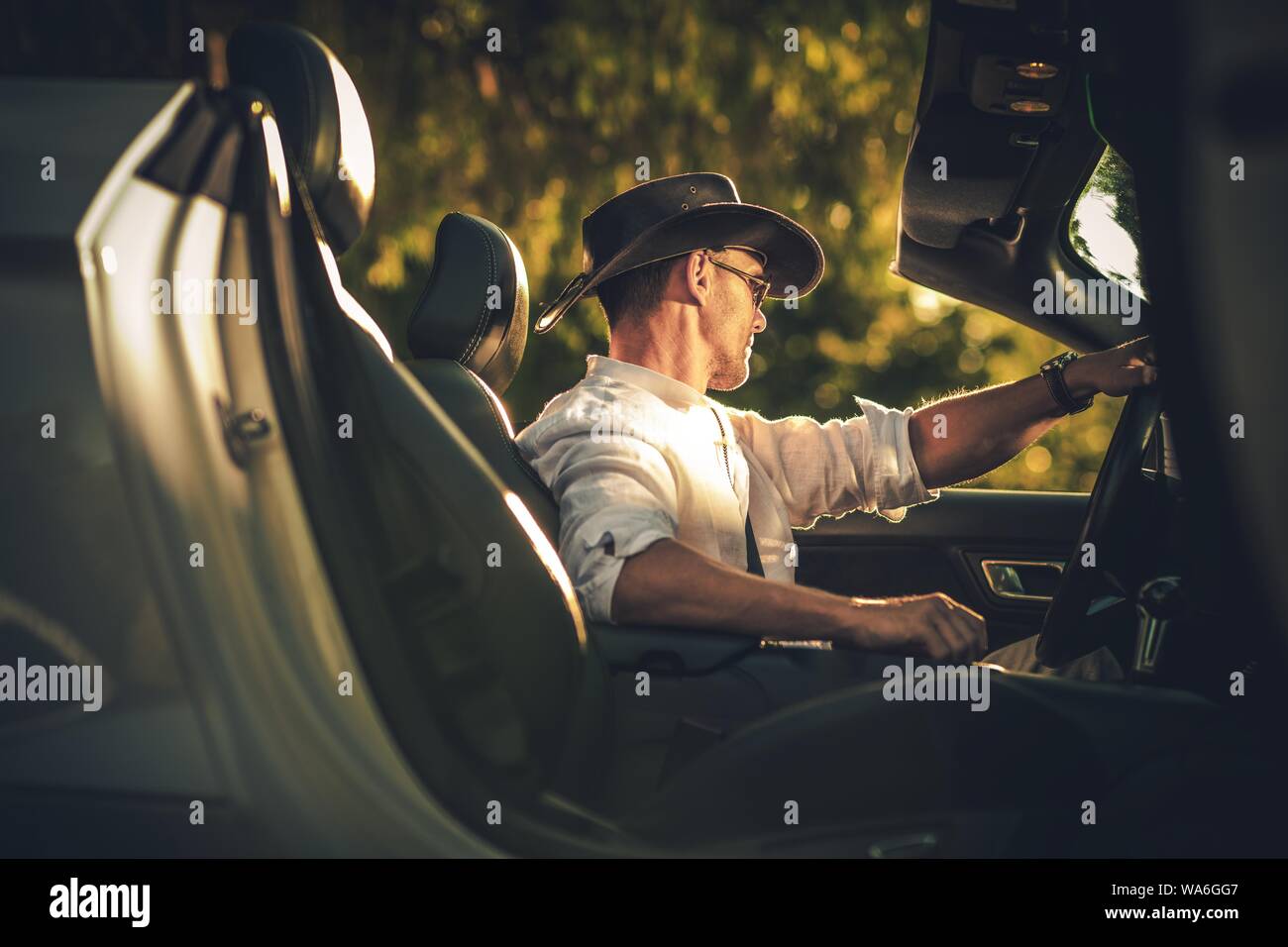 Cowboy caucasica indossando elegante Cappello in cuoio guida Cabriolet moderna durante l estate giornata di sole. Foto Stock