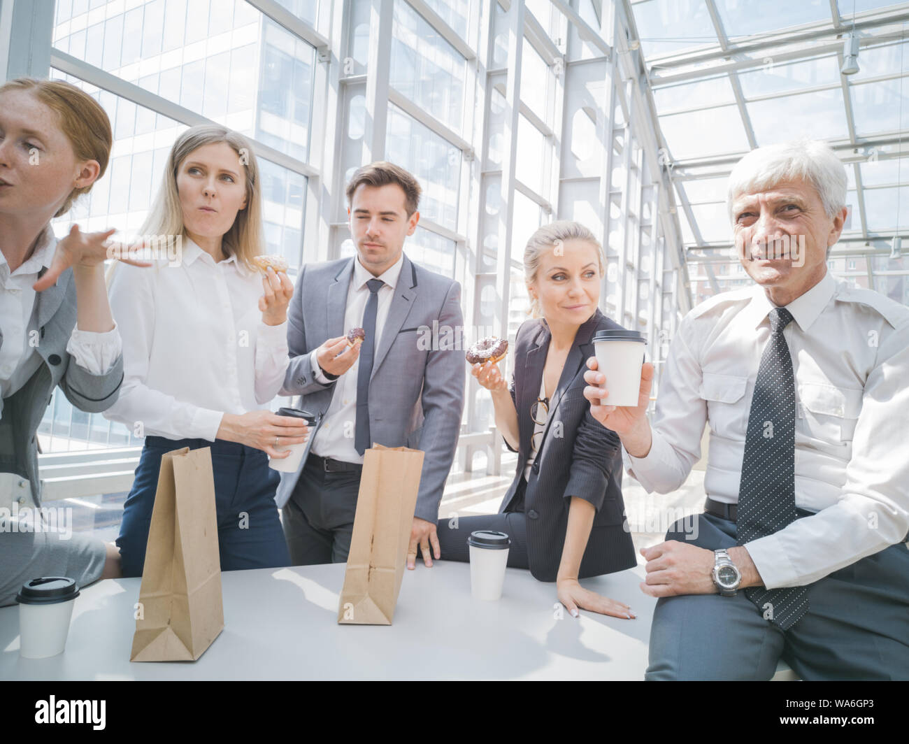 La gente di affari con pausa caffè ciambelle mangiare insieme in ufficio Foto Stock