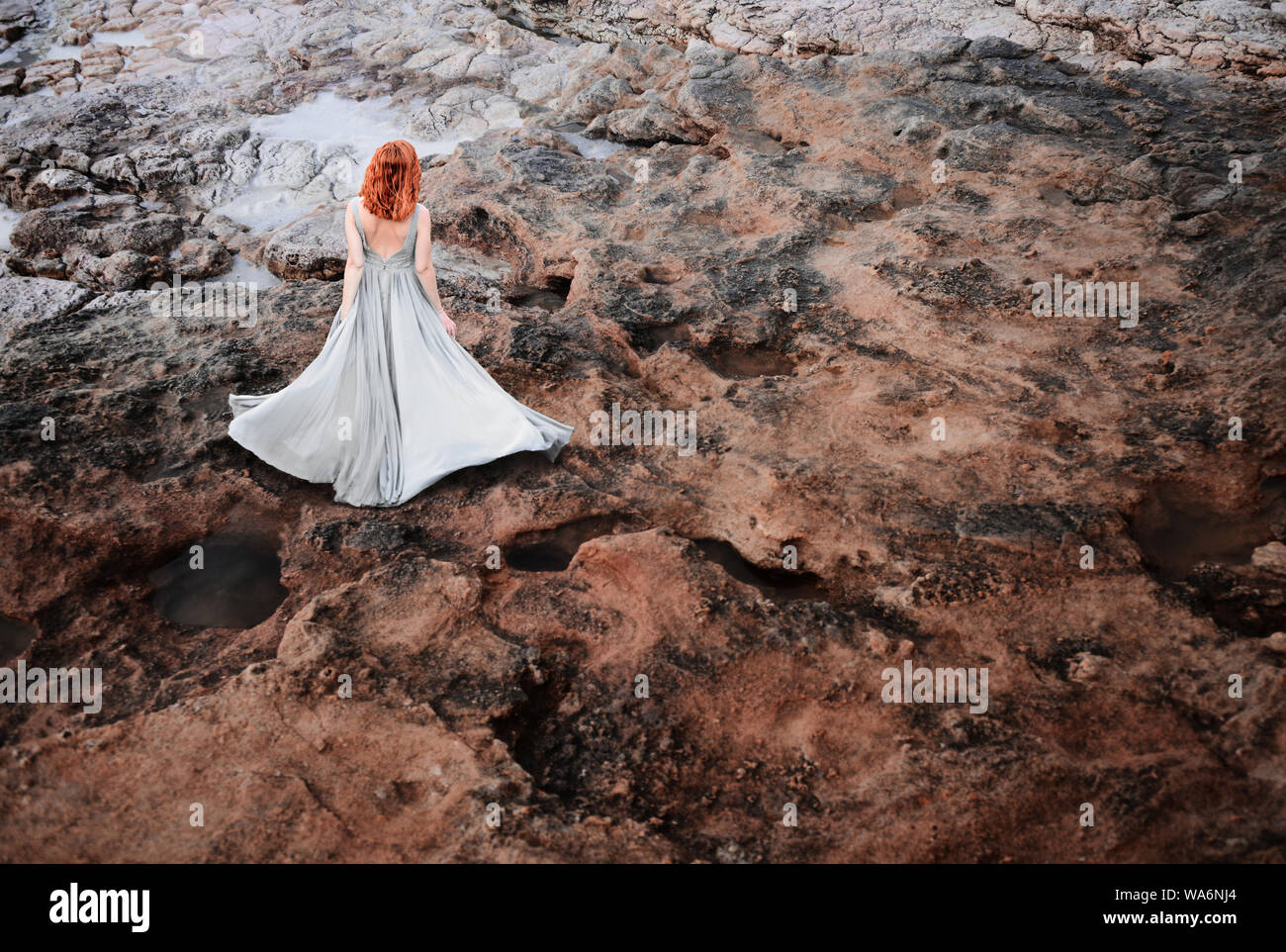 Bella giovane donna in abito elegante sulla superficie rocciosa Foto Stock