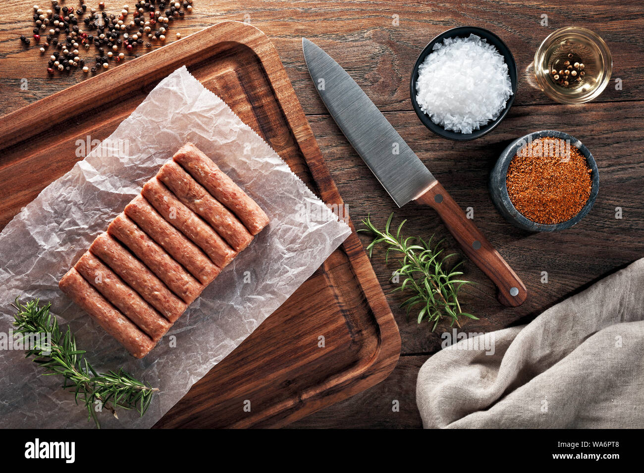 Materie turco polpette inegol sul bianco di carta di cottura e tavolo in legno. Decorate con sale e pepe, carne coltello e igienico. Vista aerea. Foto Stock