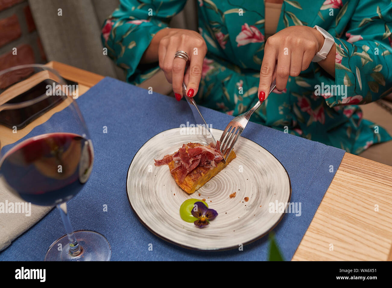 Donna tagli piatti secondo le regole del galateo in un abito verde close-up Foto Stock