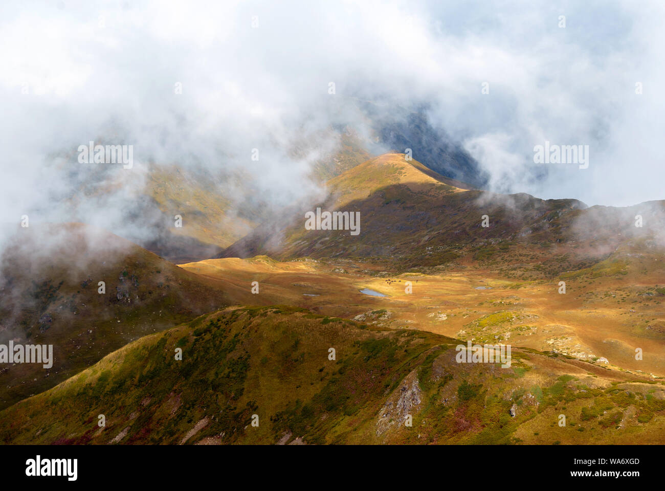 Nuvole-coperto alta valle di montagna con un lago, vista aerea Foto Stock