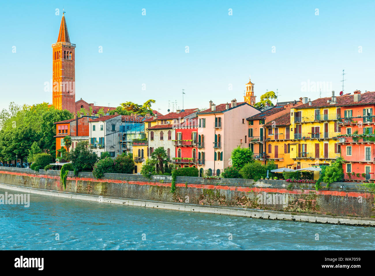 Gli edifici colorati e la vecchia chiesa medievale sulla banca del fiume di Verona, regione Veneto, Italia, Europa Foto Stock