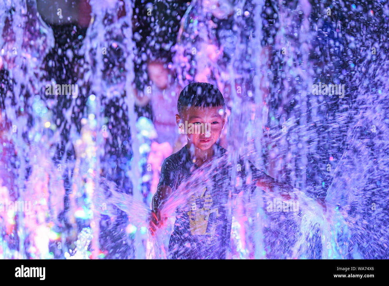 (190818) -- CHONGQING, Agosto 18, 2019 (Xinhua) -- Un ragazzo gioca con acqua ad una fontana musicale in Nan"di un distretto del sud-ovest della Cina della Municipalità di Chongqing, Agosto 17, 2019. Maggior vigore è stata versata in Chongqing sera economia come le autorità locali a migliorare lo zoning dei mercati di notte, la scala degli investimenti sul mercato notturno branding e strutture, incoraggiando nel contempo la spesa dei consumatori con la notte di attività per il tempo libero. (Xinhua/Wang Quanchao) Foto Stock