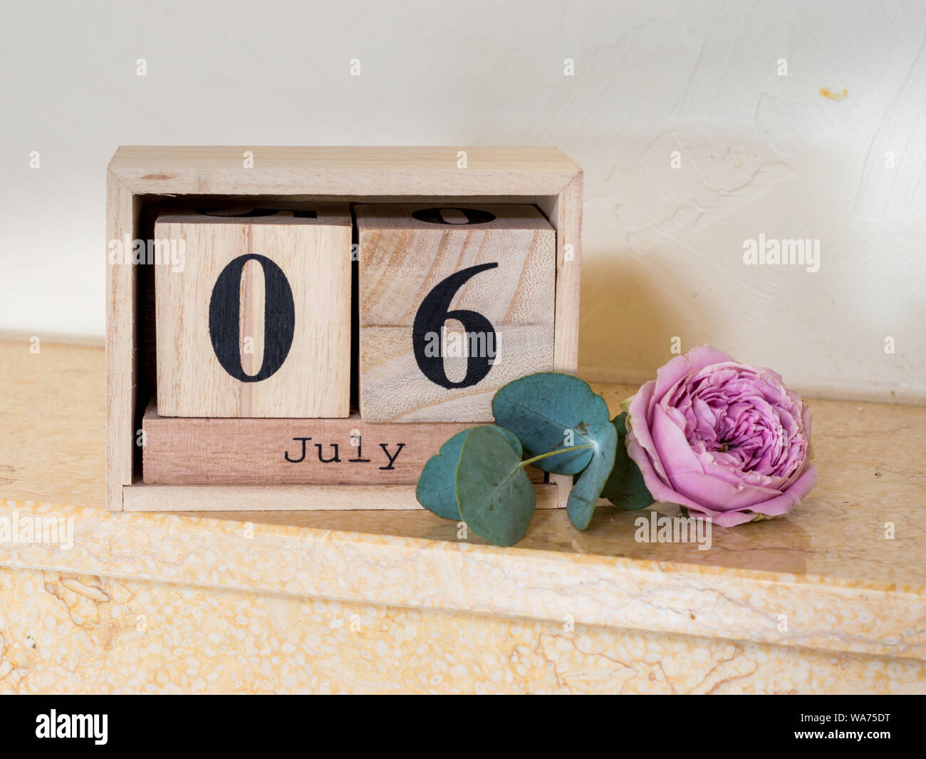 Data di legno i cubi su luglio 6 e di un bocciolo di rosa Foto Stock