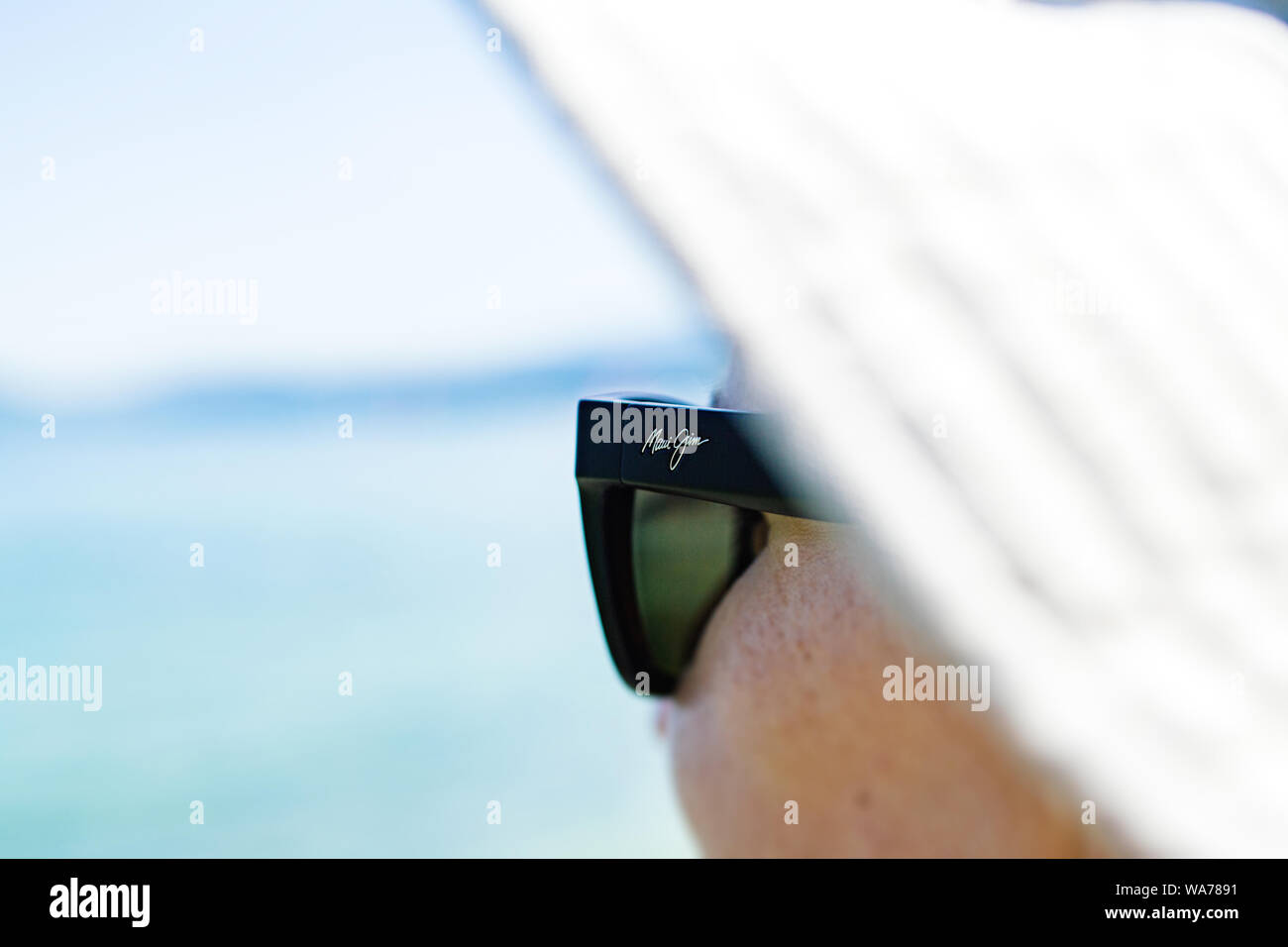 Il Principato di Monaco, Francia - 15 AGO 2017: Donna con protezione solare hat indossando Maui Jim occhiali da sole con sfocati oceano mare in background Foto Stock