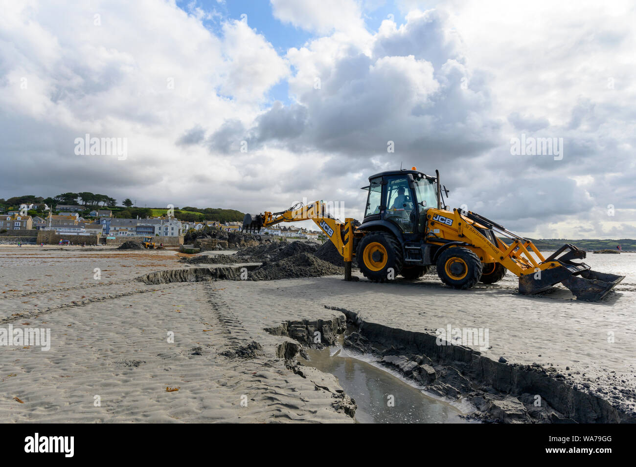 JCB escavatrice, scavando un canale nella sabbia per il turista traghetti, St Michael's Mount, Marazion, vicino a Penzance, Cornwall, Regno Unito Foto Stock