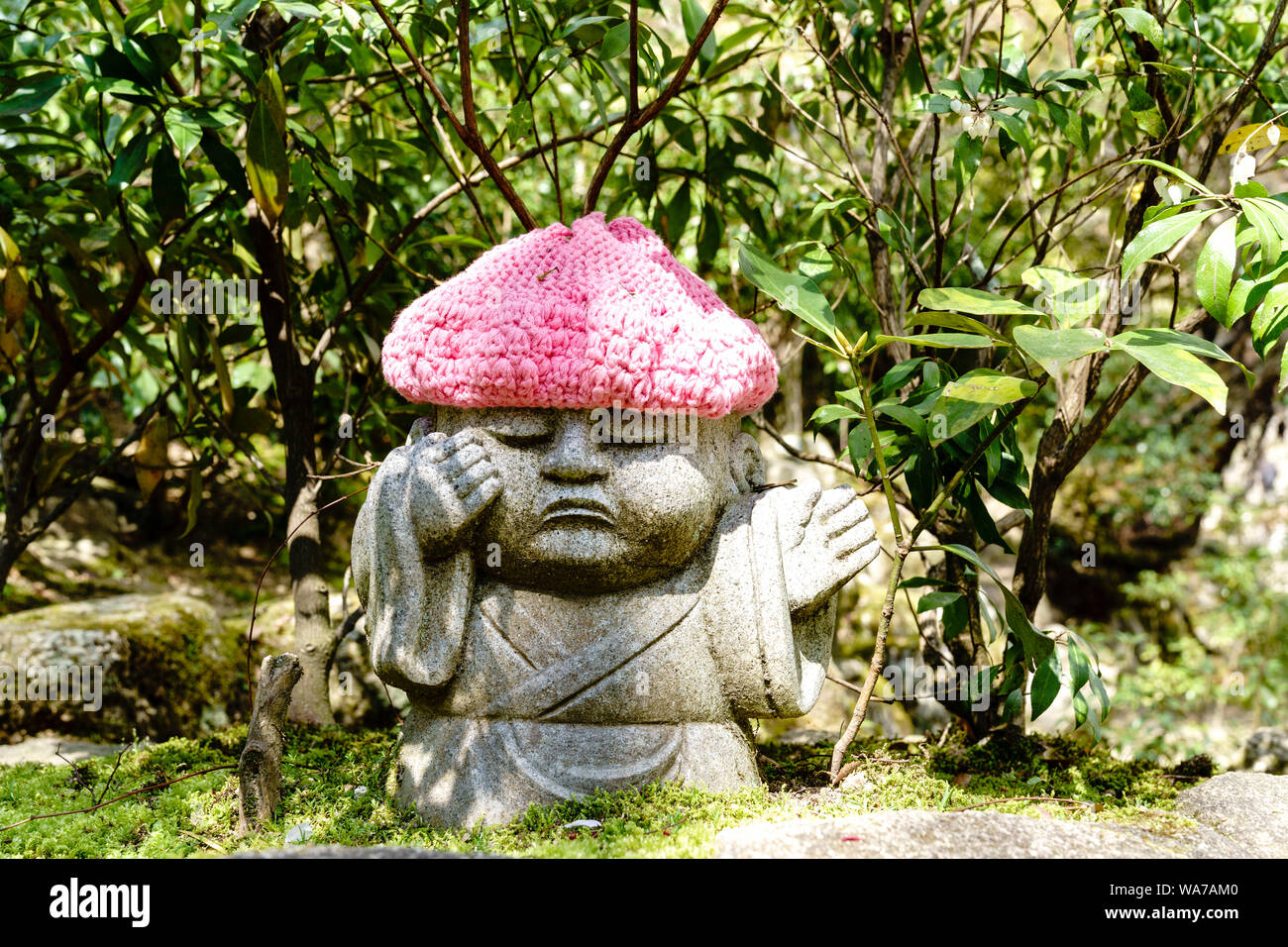 Giappone, Miyajima. Daisho-nel tempio. Rakan piccola statua di un monaco buddista, con rosa cappello di lana, con faccia infelice, assomiglia a dirigere il traffico. Foto Stock