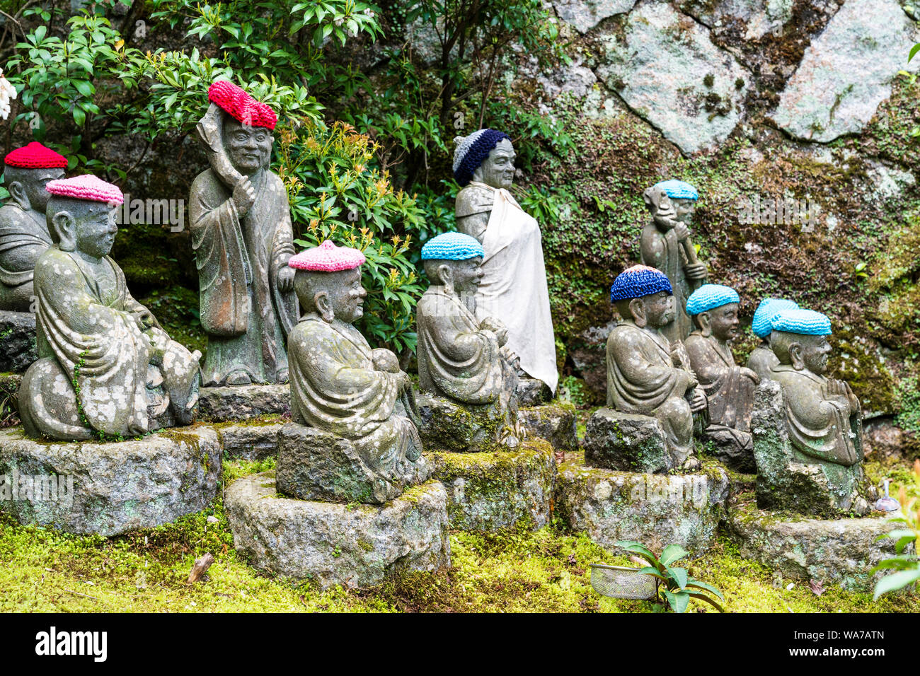 Giappone, Miyajima. Rakan piccole statue di monaci buddisti, discepoli di Shaka, rivestimento gradino di pietra percorso attraverso l'entrata del Daisho-nel tempio. Foto Stock
