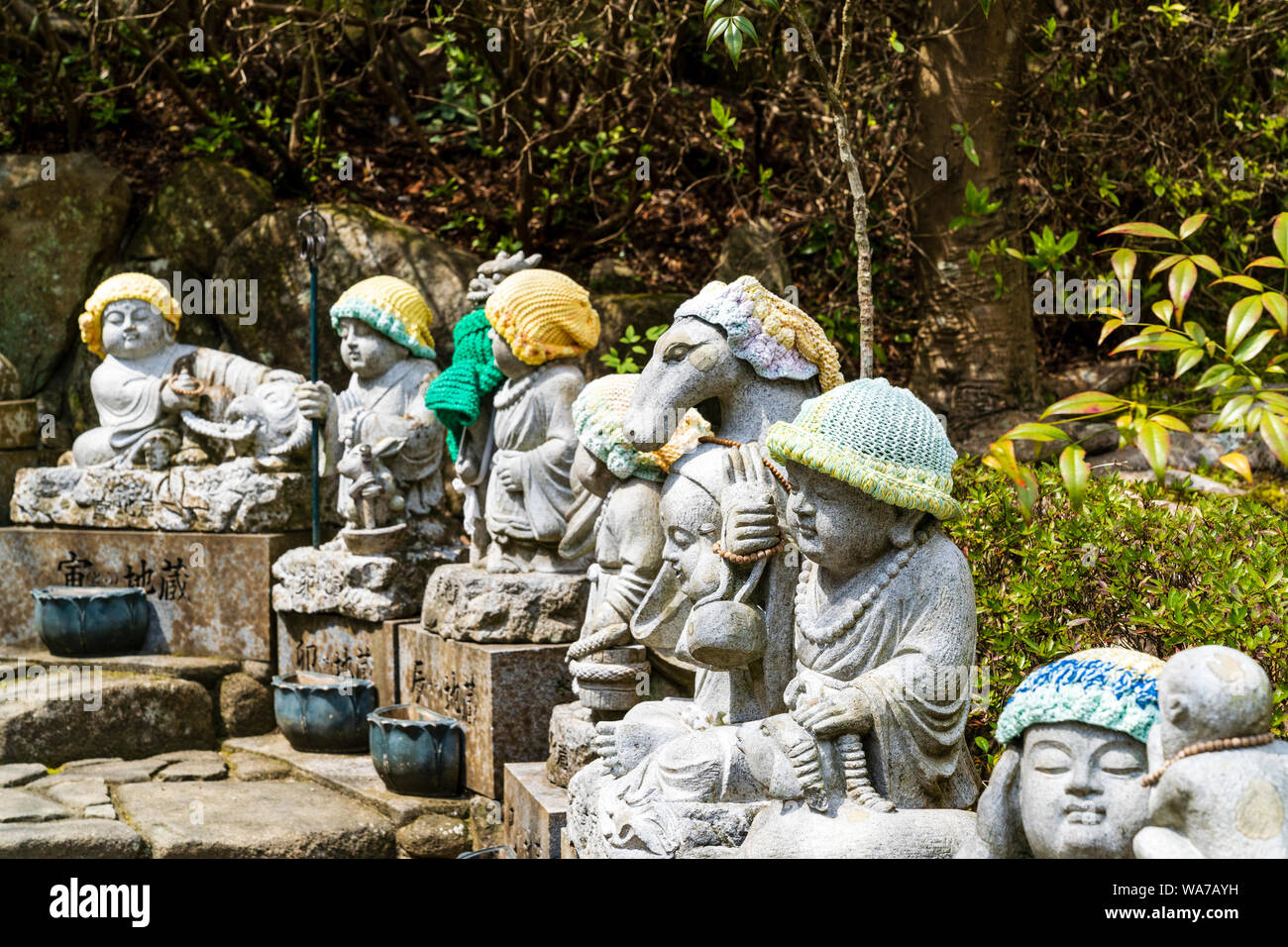 Giappone, Miyajima. Daisho-nel tempio. Fila di piccola pietra Jizo statue di monaci buddisti, tutti diversi. Tutti hanno lavorato a maglia cappelli di lana su Foto Stock
