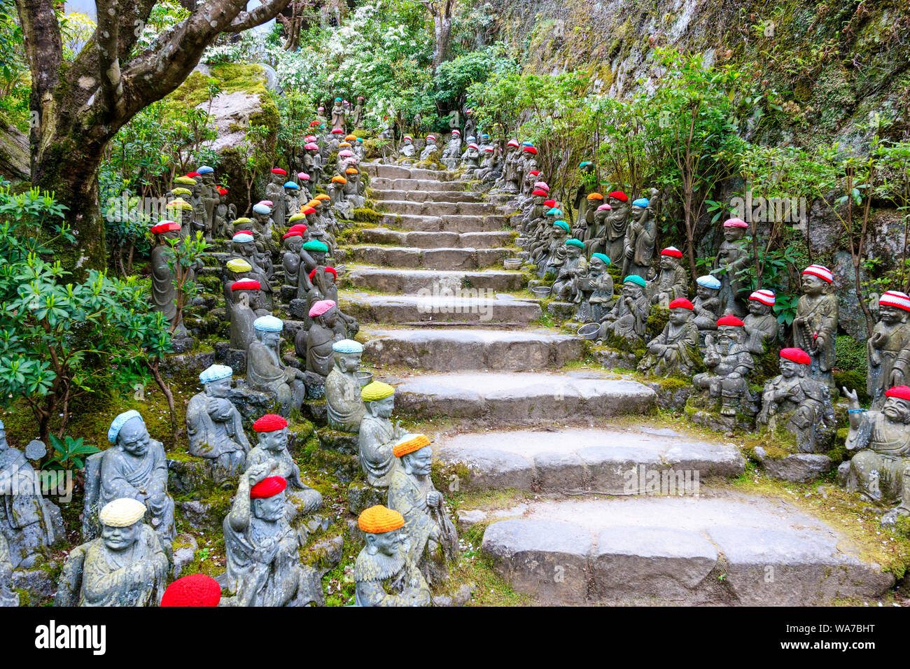 Giappone, Miyajima. Rakan piccole statue di monaci buddisti, discepoli di Shaka, rivestimento gradino di pietra percorso attraverso l'entrata del Daisho-nel tempio. Foto Stock