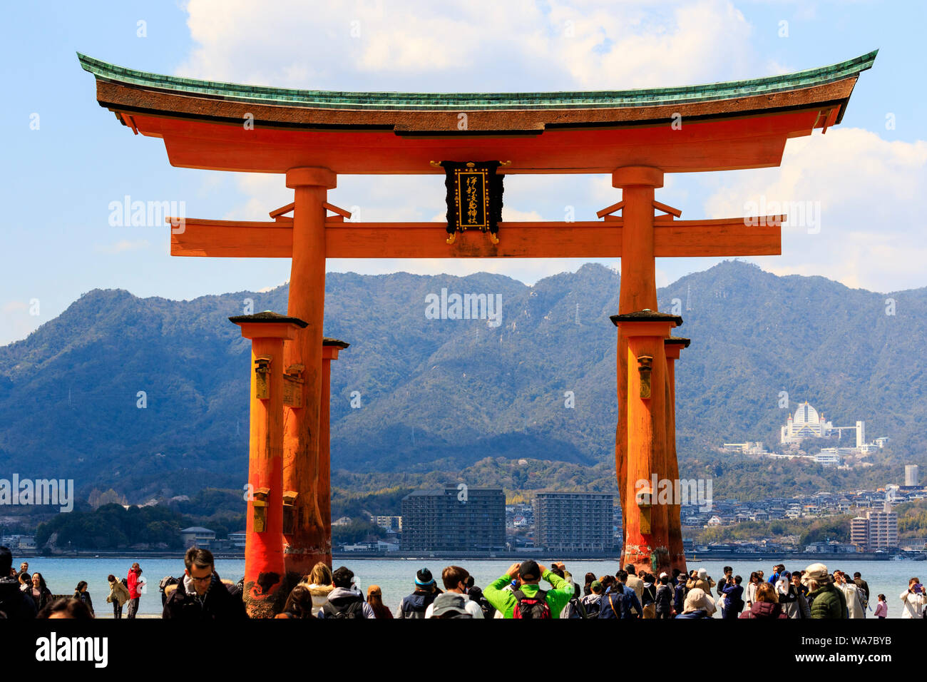 Giappone, Miyajima. Il grande Torii, o Otorii del santuario di Itsukushima. Red Torii sulla sabbia a marea e molte persone che camminano intorno ad esso. Foto Stock