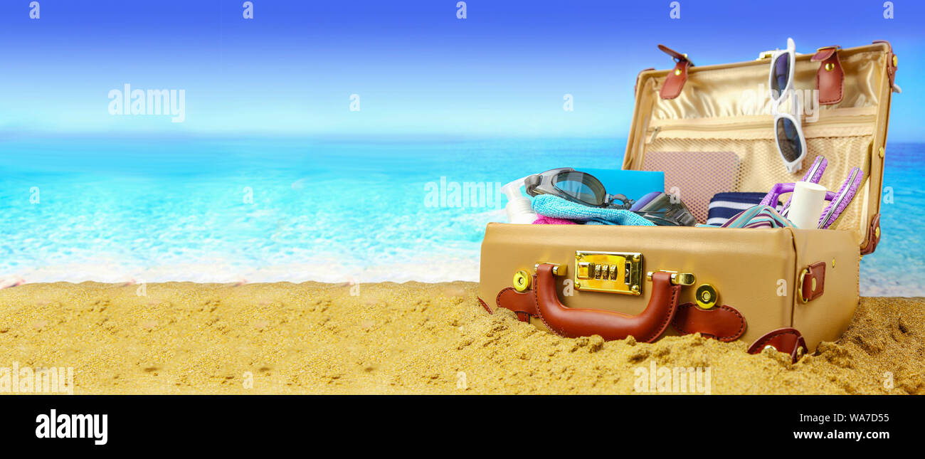 Aprire completamente la valigia sulla spiaggia tropicale sfondo, banner Foto Stock