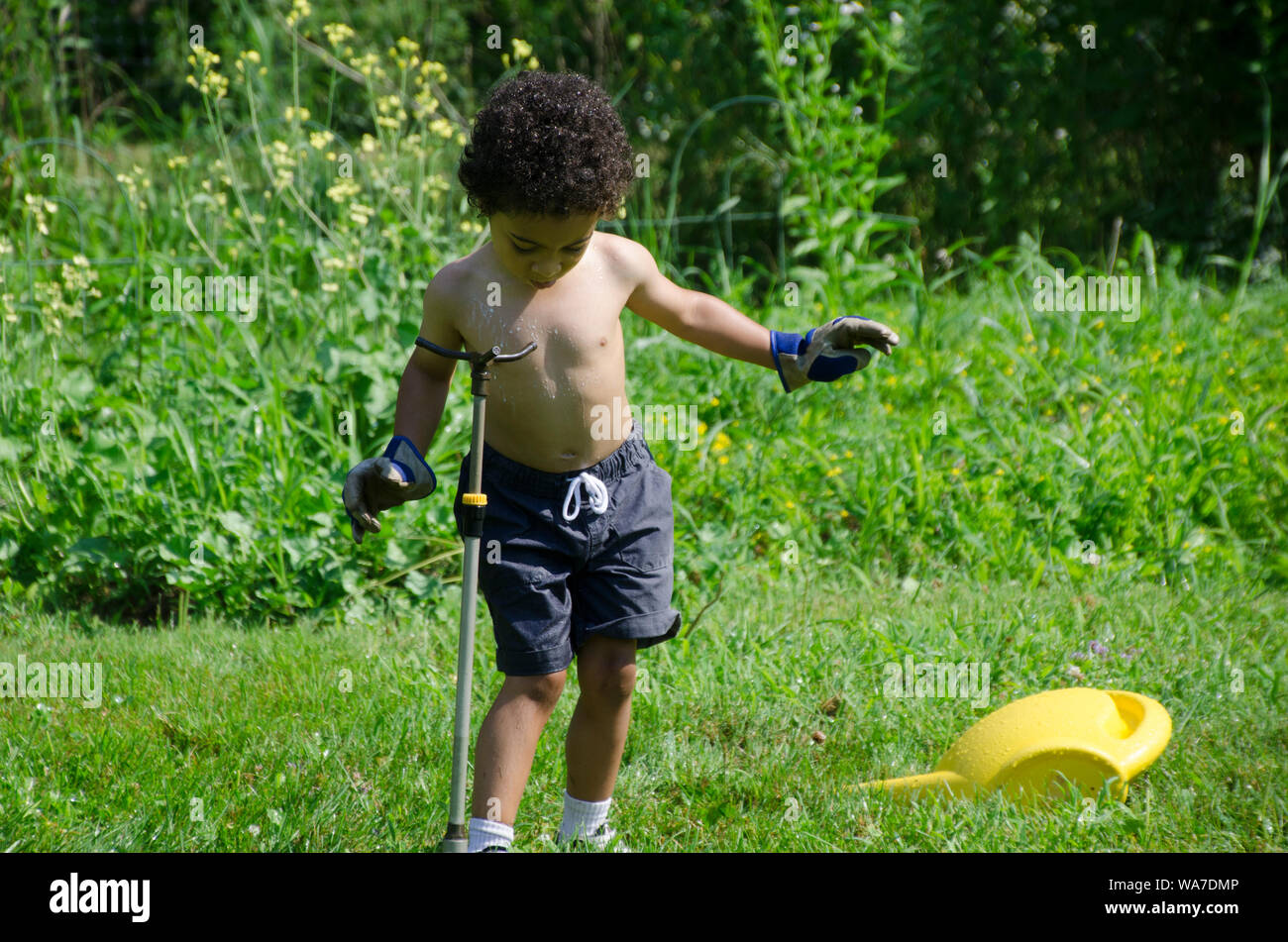 Ragazzo giocando in impianti sprinkler nel giardino estivo, Yarmouth comunità giardino, Maine, Stati Uniti d'America Foto Stock