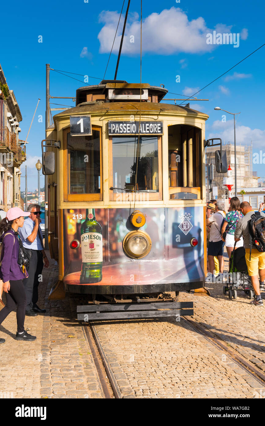 Portogallo Porto Porto Ribeira old street car il tram n. 1 direzione di arresto Passeiro Alegre guide linee persone ciottoli advert Jameson Irish whiskey nuvole Foto Stock