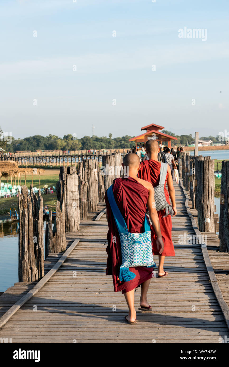 MANDALAY, MYANMAR - 03 dicembre, 2018: immagine verticale di monaci buddisti attraversando a piedi il legno U Bein Bridge durante la giornata di sole a Mandalay, Myanm Foto Stock