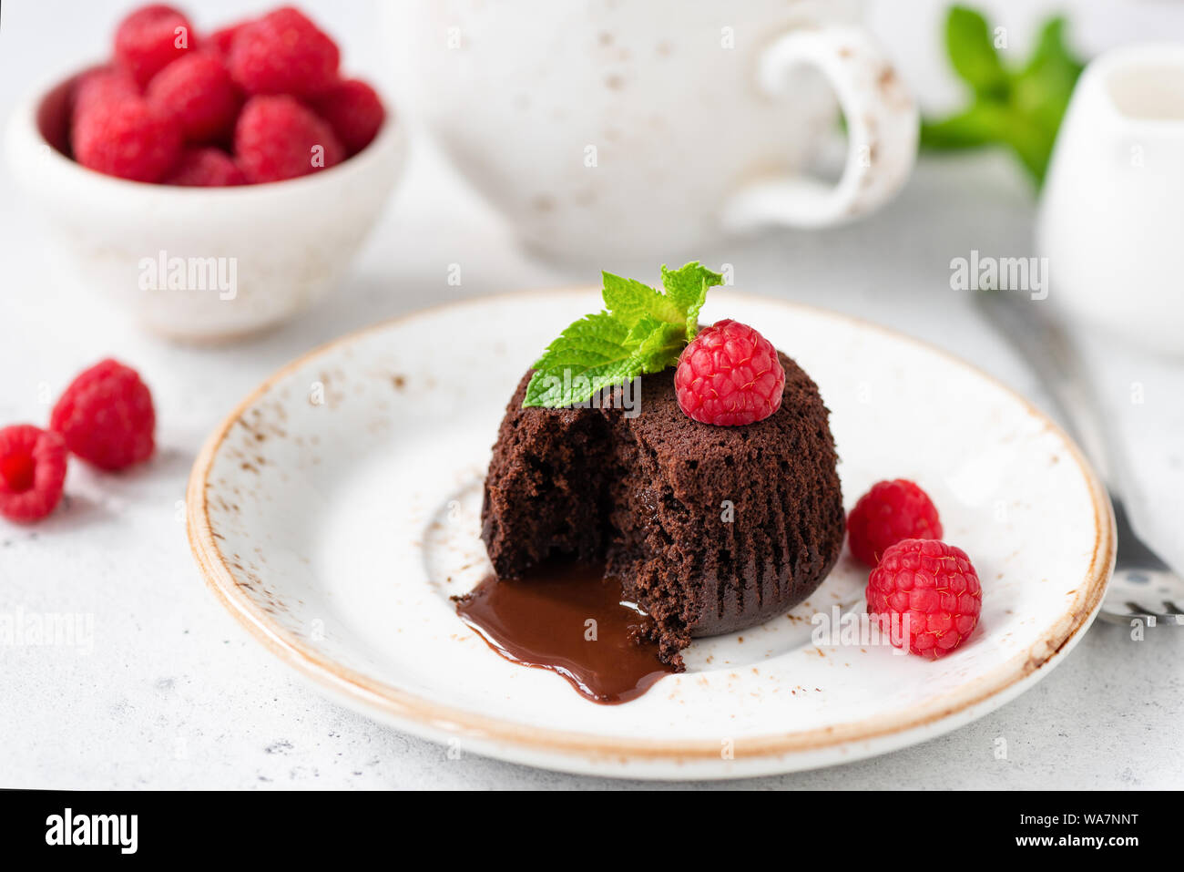 Cioccolato torta di lava con nucleo fuso sulla piastra bianca servito con lamponi freschi e foglia di menta Foto Stock