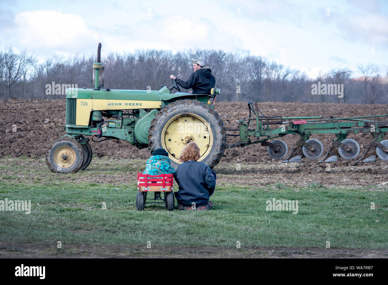 Aprile 28 2018 Buchanan MI USA; mamma e bambino sta guardando il coltivatore aratro suo campo Foto Stock