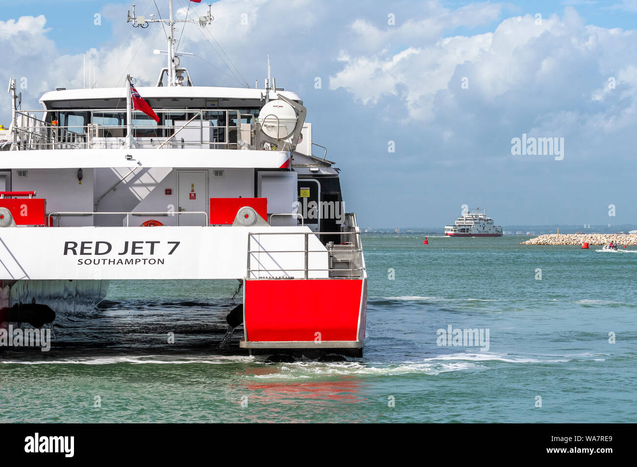 Red Jet 7 lasciando West Cowes, Isle of Wight con il traghetto del veicolo nella distanza entrando nel porto di Southampton, Hampshire, Inghilterra, Regno Unito Foto Stock
