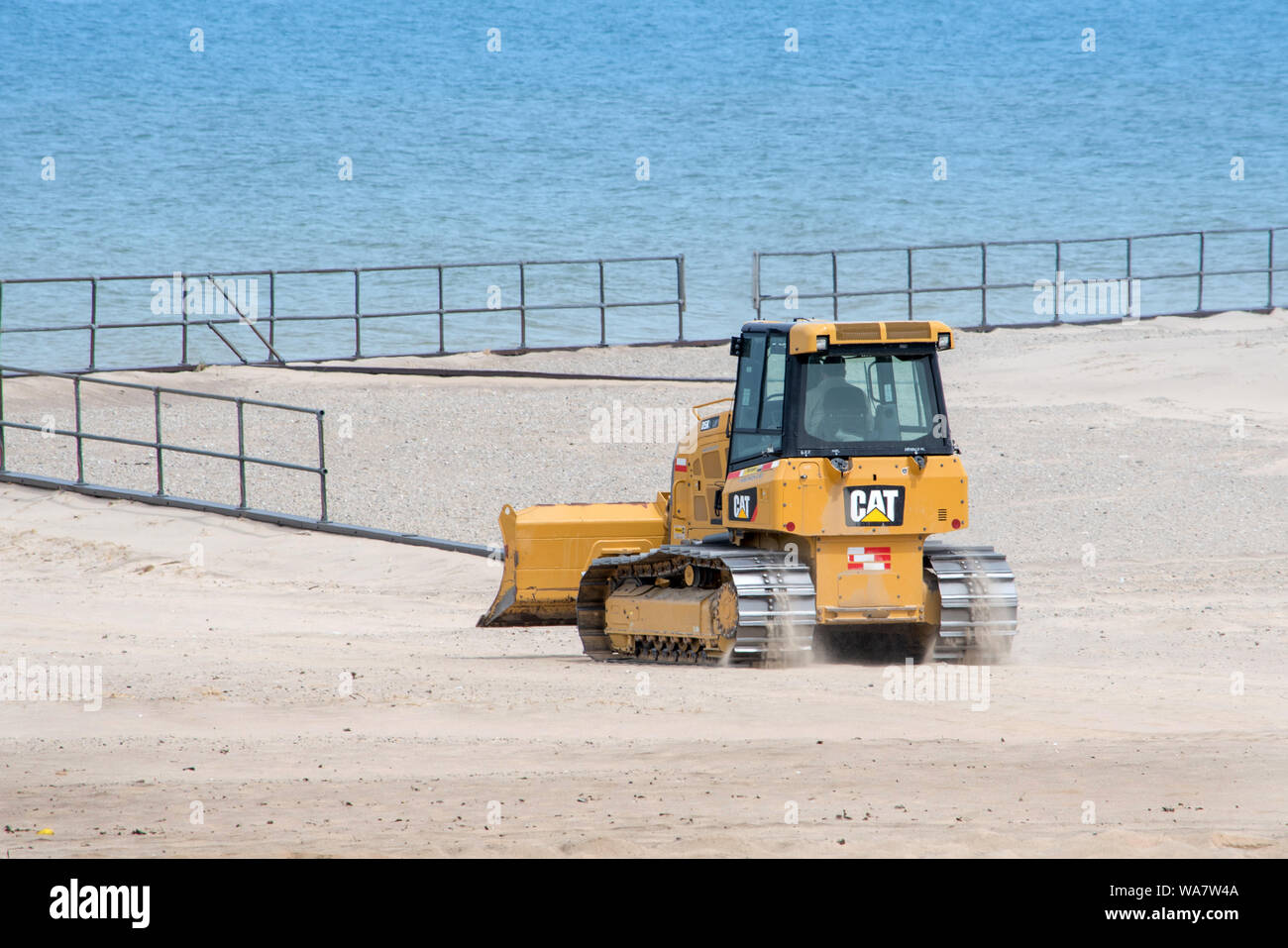 Lavoratore utilizza un piccolo bulldozer per rimuovere sabbia deriva da un parcheggio sulle rive del lago Michigan, in un parco statale Foto Stock