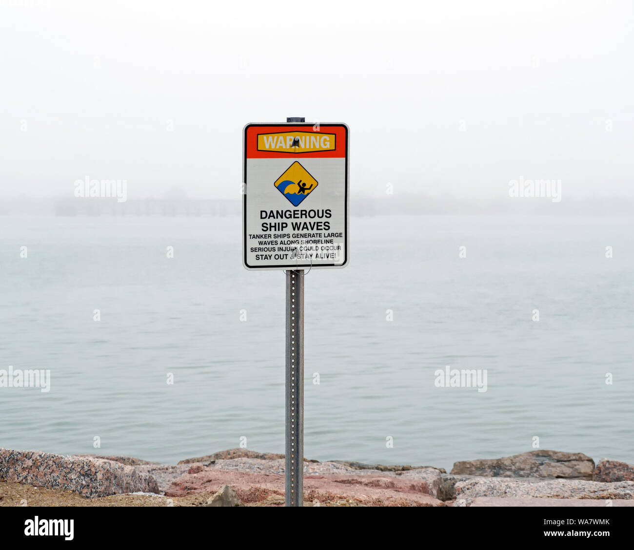 Un segno inviato al porto Aransas molo sud avverte di pericolose onde generate dal passaggio di navi cisterna. Foto scattata nella fitta nebbia. Foto Stock