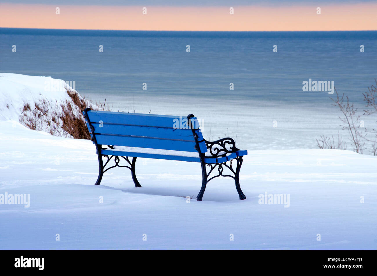 Un freddo vuoto azzurro una panchina nel parco si affaccia un gelido lago michigan nelle tonalità del bianco e del blu. Foto Stock
