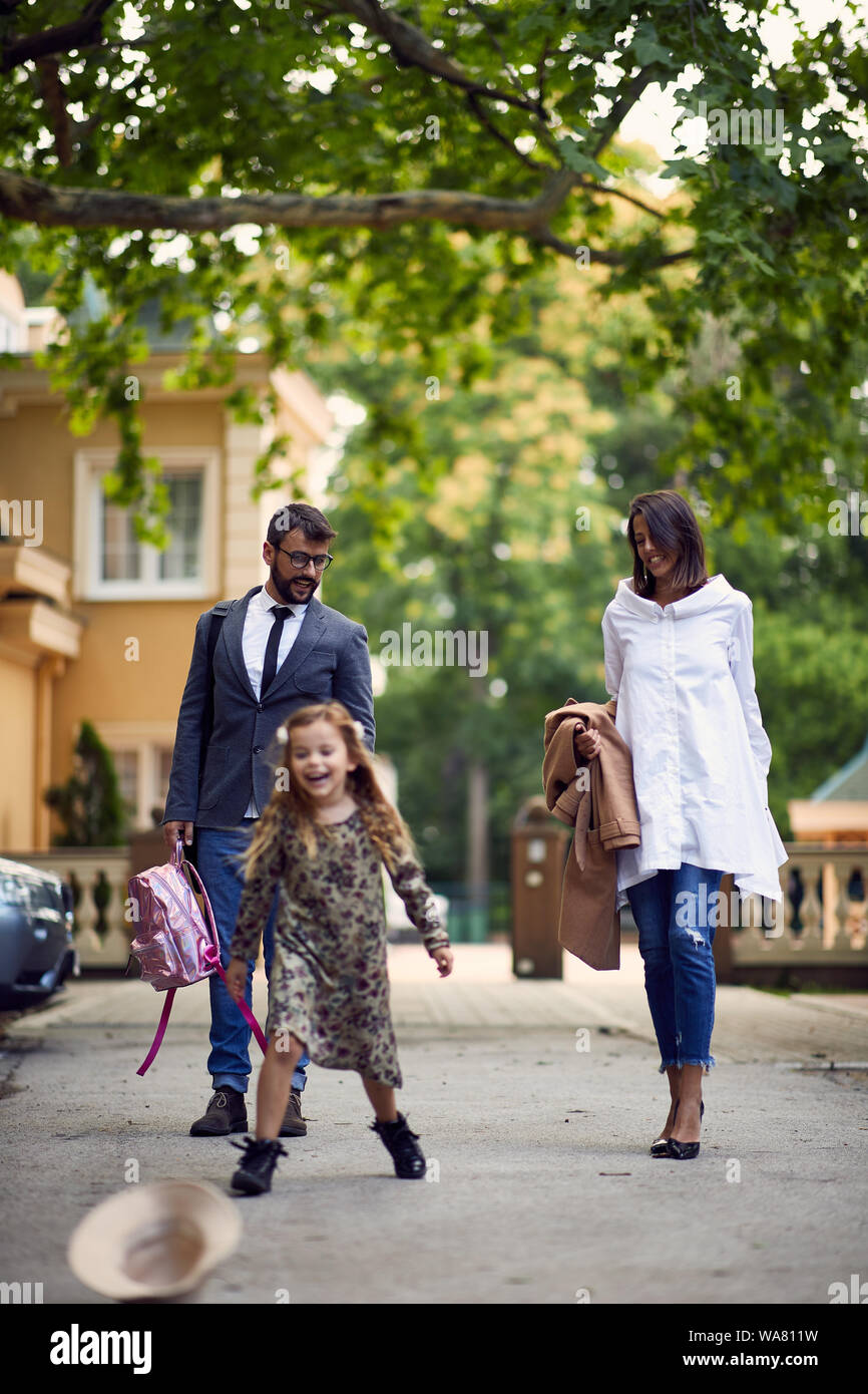 Young business i genitori a piedi con vi figlia dopo la scuola Foto Stock