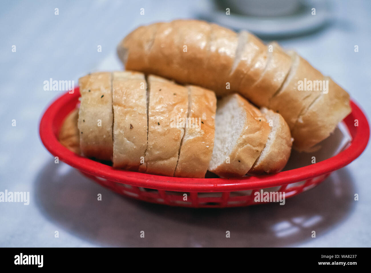 Pane italiano, tagliato a fette e calda di forno, in un rosso cestino per pane Foto Stock