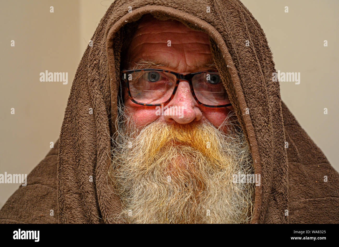 Uomo anziano indossando incappucciati coperta per tenere in caldo Foto Stock