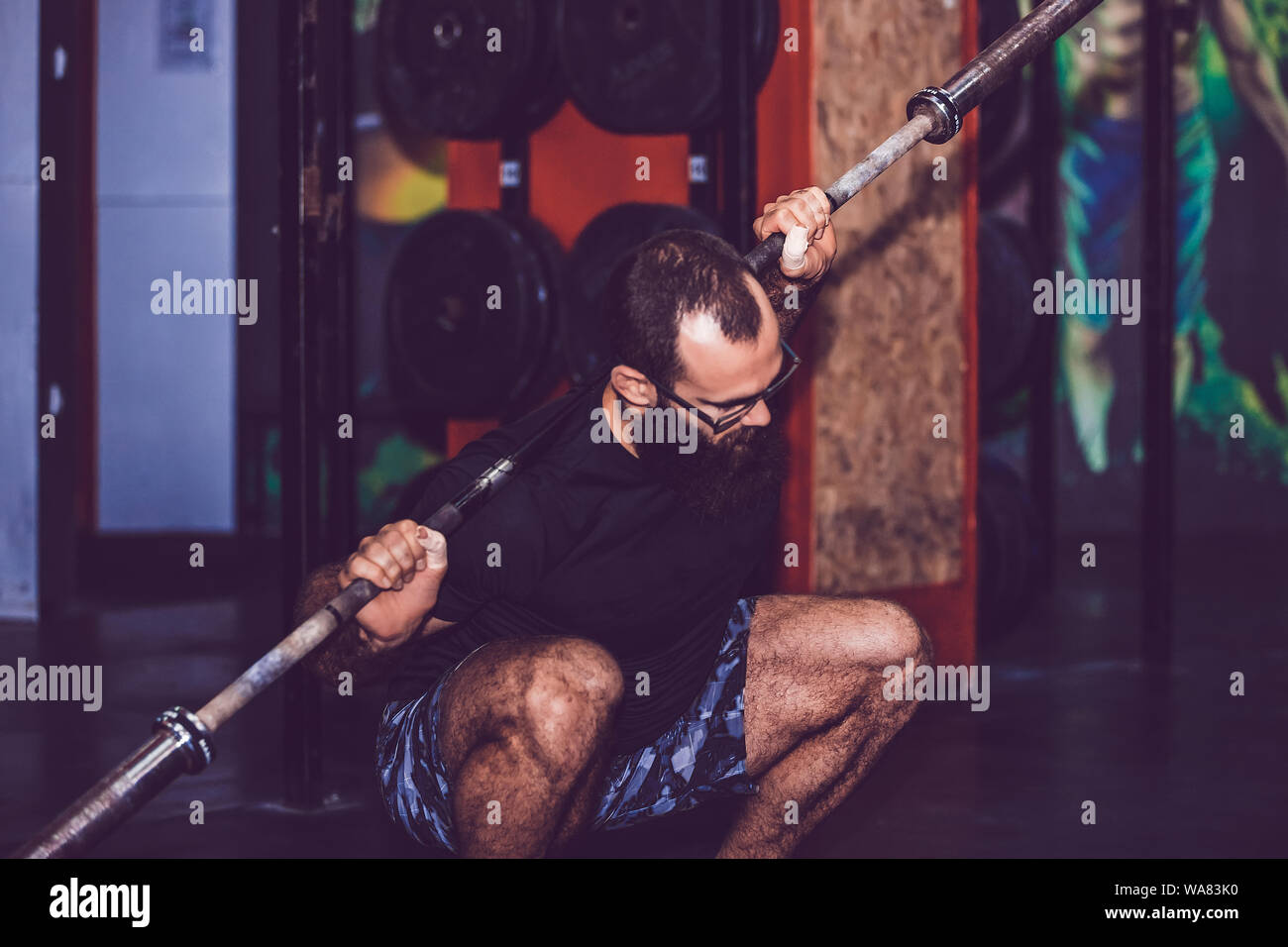Giovane uomo barbuto facendo warm up esercizi con i pesi in palestra Foto Stock