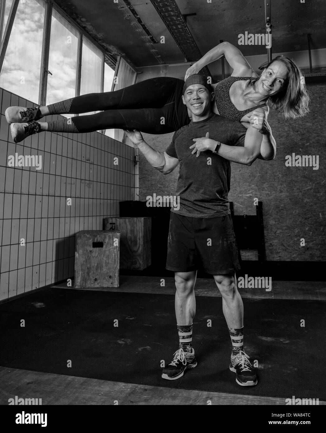 Un atletico bella giovane sorride, facendo un allenamento fitness insieme e divertirsi.L'uomo muscolare è in attesa di montare la donna sulle sue spalle. Foto Stock