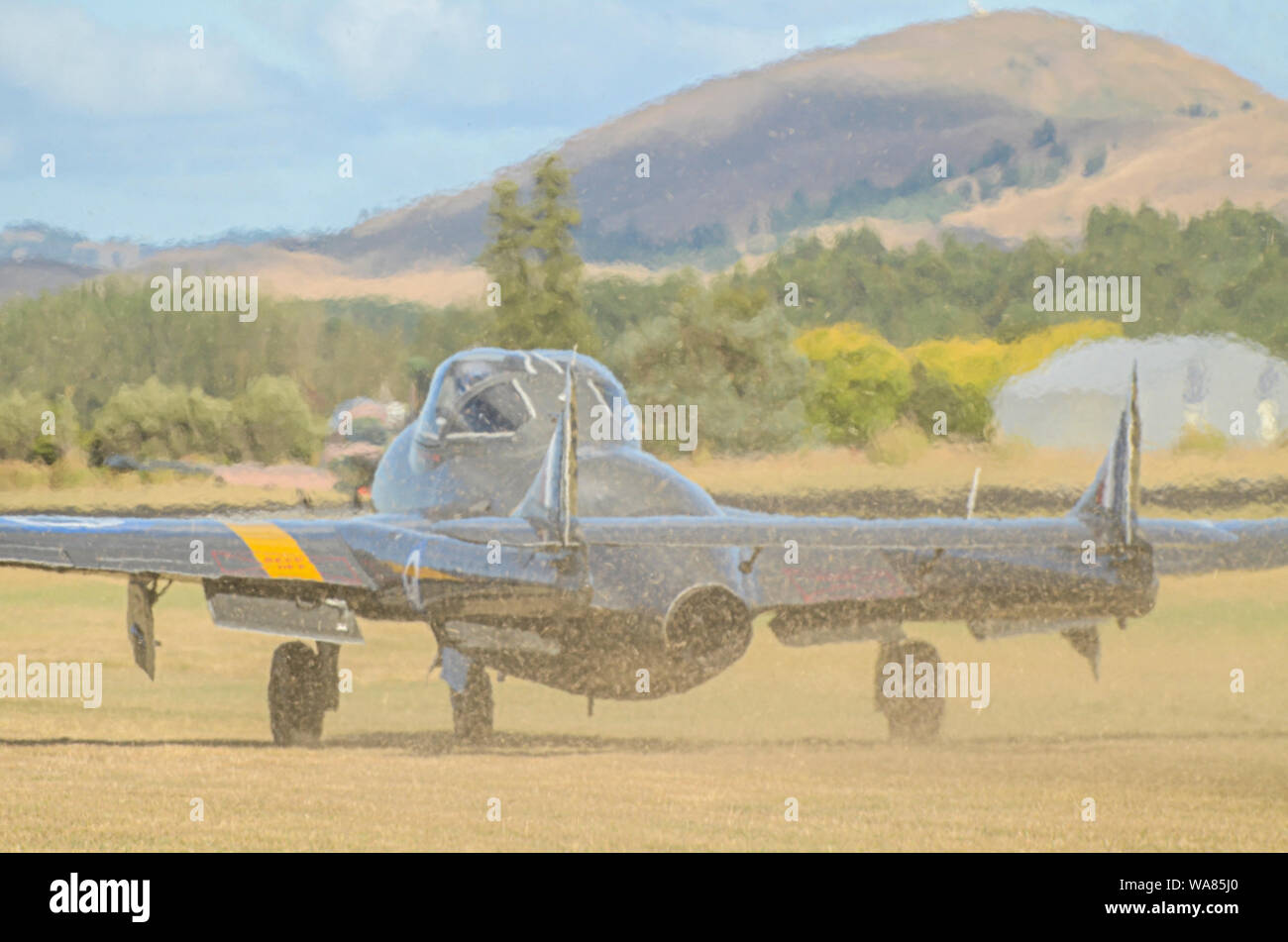De Havilland Vampire jet piano ad ali su airshow Wairarapa, cappa Aerodrome, Masterton, Nuova Zelanda. Il rullaggio su erba che soffia su tagli di erba Foto Stock