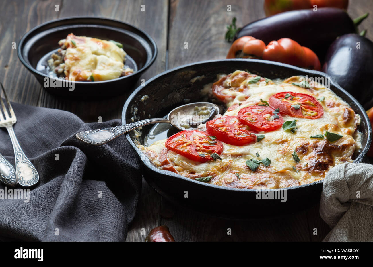 Freschi Fatti in casa La moussaka in padella di ferro su legno rustico sfondo con ingredienti. La cucina greca. Foto Stock