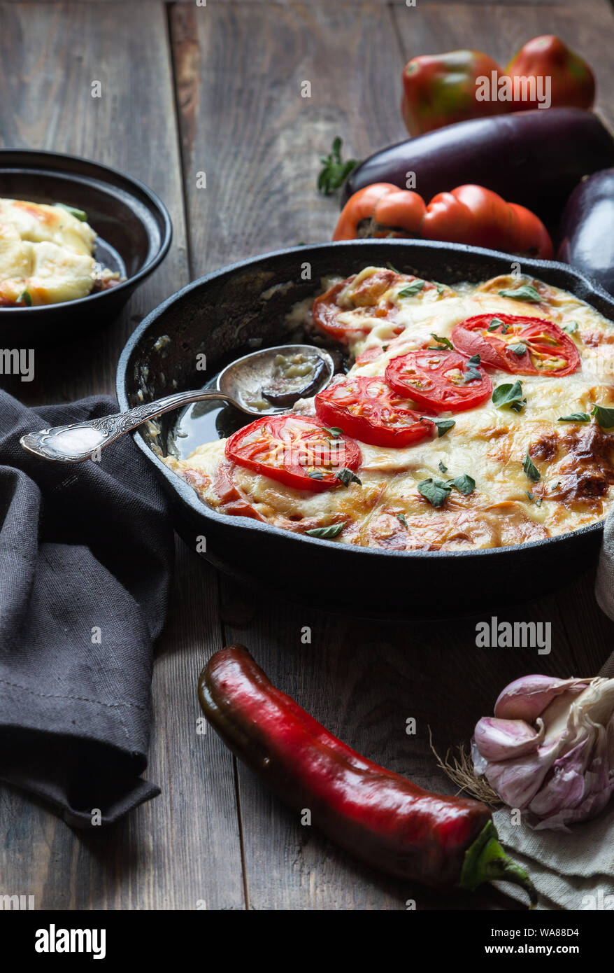 Freschi Fatti in casa La moussaka in padella di ferro su legno rustico sfondo con ingredienti. La cucina greca. Foto Stock