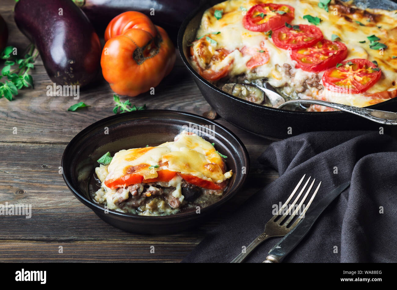 Freschi Fatti in casa La moussaka in padella di ferro su legno rustico sfondo con ingredienti. La cucina greca. Foto Stock