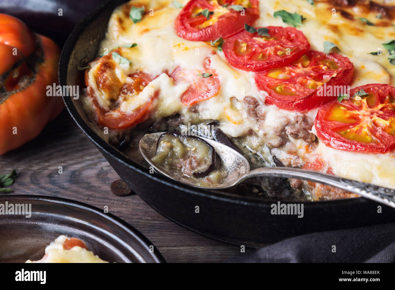 Freschi Fatti in casa La moussaka in padella di ferro su legno rustico sfondo con ingredienti. La cucina greca. Foto Stock