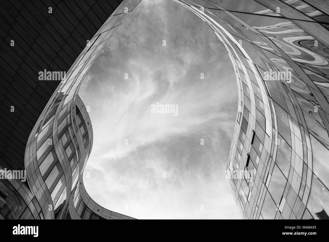 Basso angolo di vista a plaza tra 2 edificio con curvatura forma libera forma del contorno. In bianco e nero di architettura astratta la facciata esterna. Foto Stock