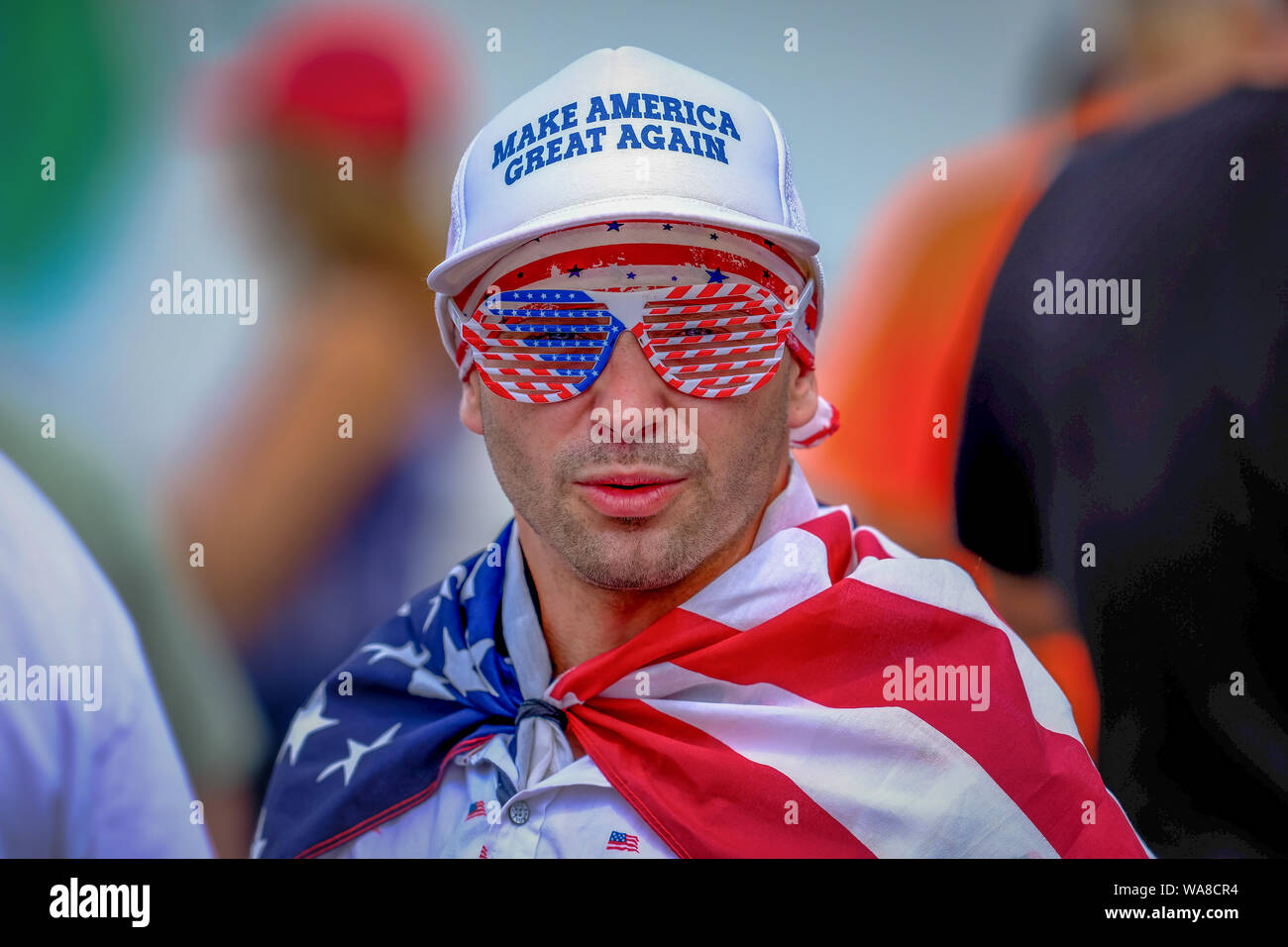 Trump sostenitore con la bandiera statunitense durante la maga Rally in New Hampshire. Foto Stock