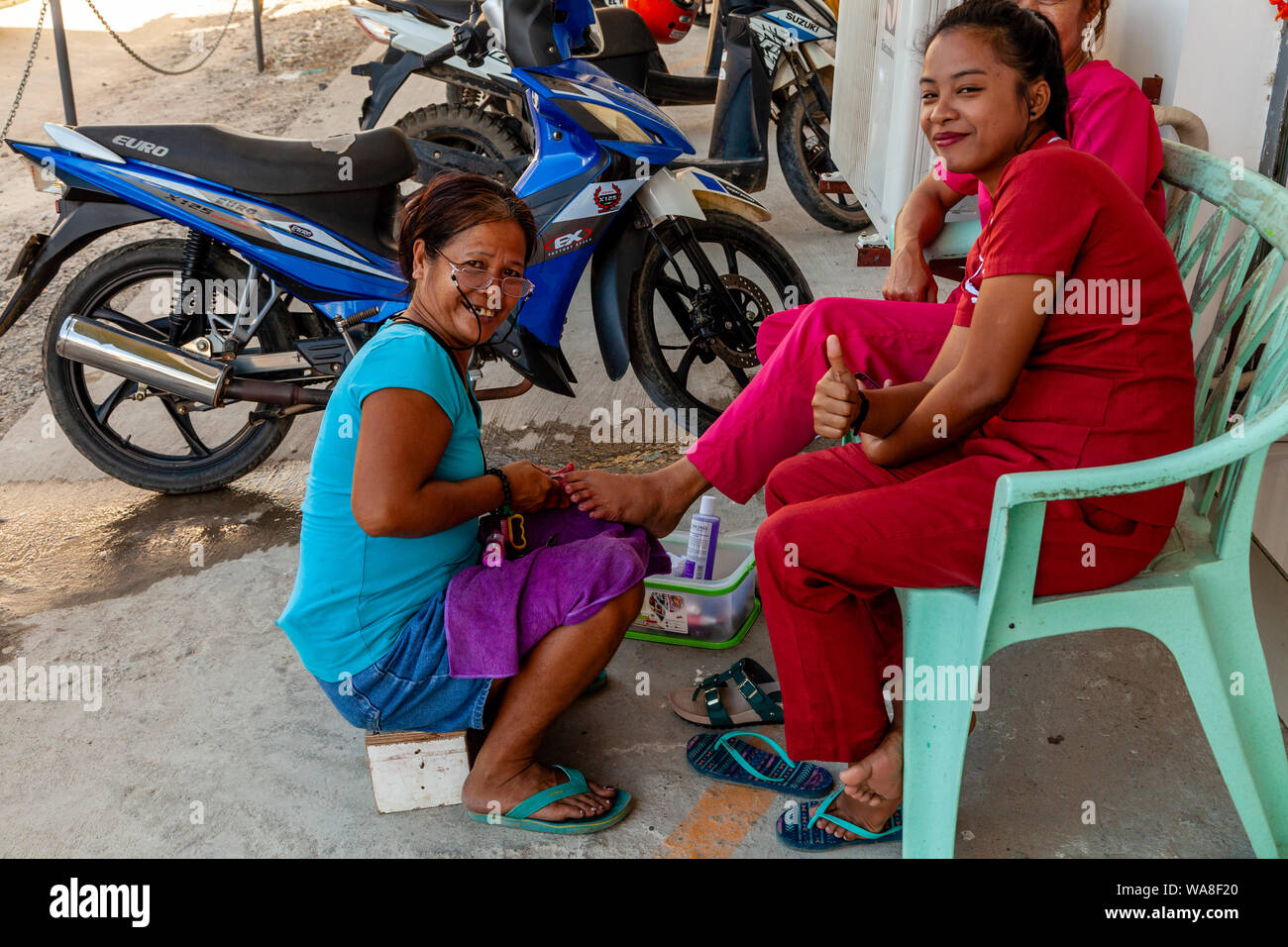Una donna locale ha una pedicure in strada, El Nido, PALAWAN FILIPPINE Foto Stock