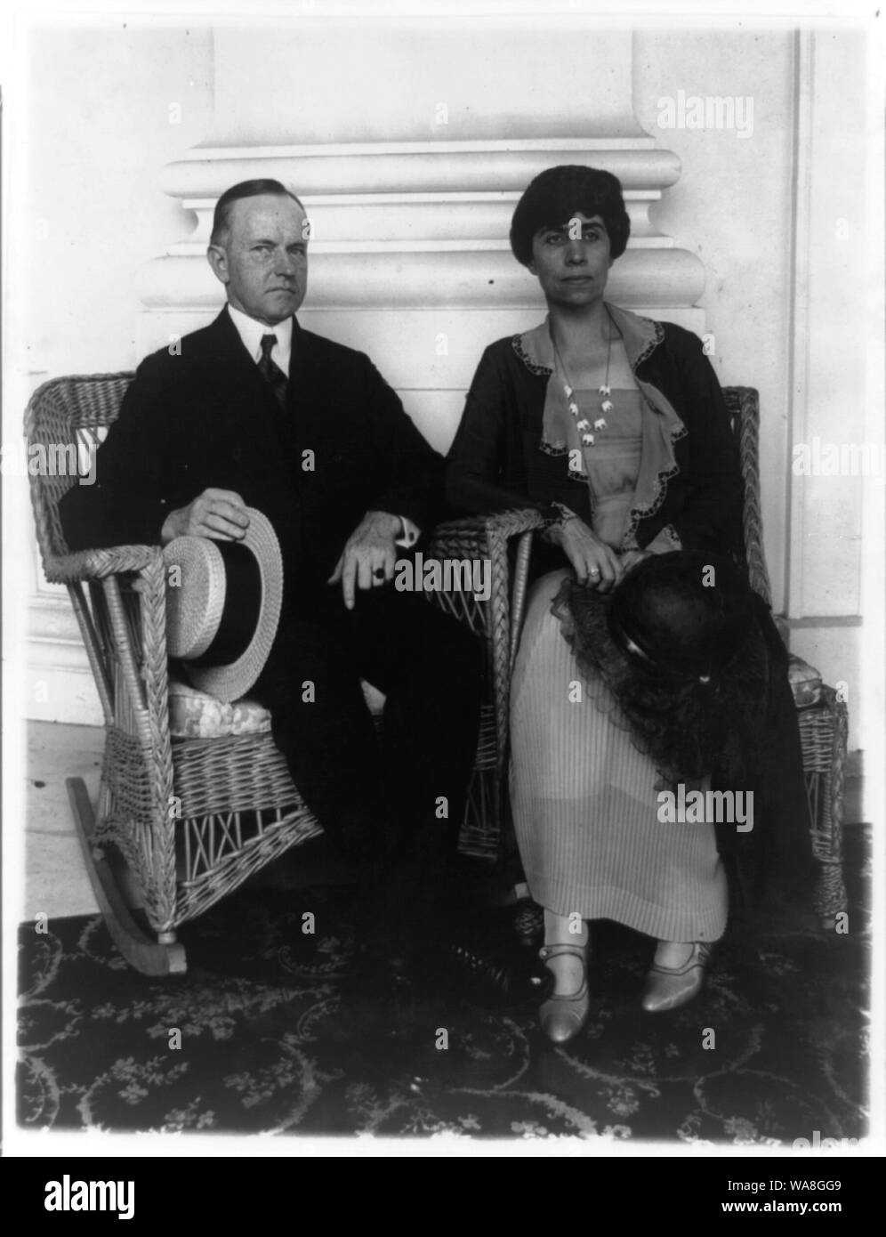 Calvin Coolidge e sua moglie di intera lunghezza verticale, seduti in poltrone in vimini Foto Stock