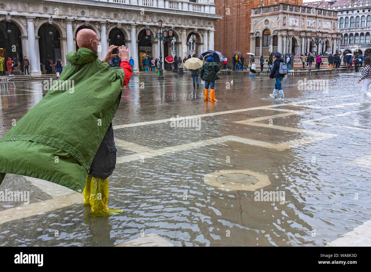 Turisti Goldon indossare stivali soprascarpe impermeabile durante l'acqua alta (l'acqua alta) evento, la Piazzetta di San Marco, Venezia, Italia Foto Stock