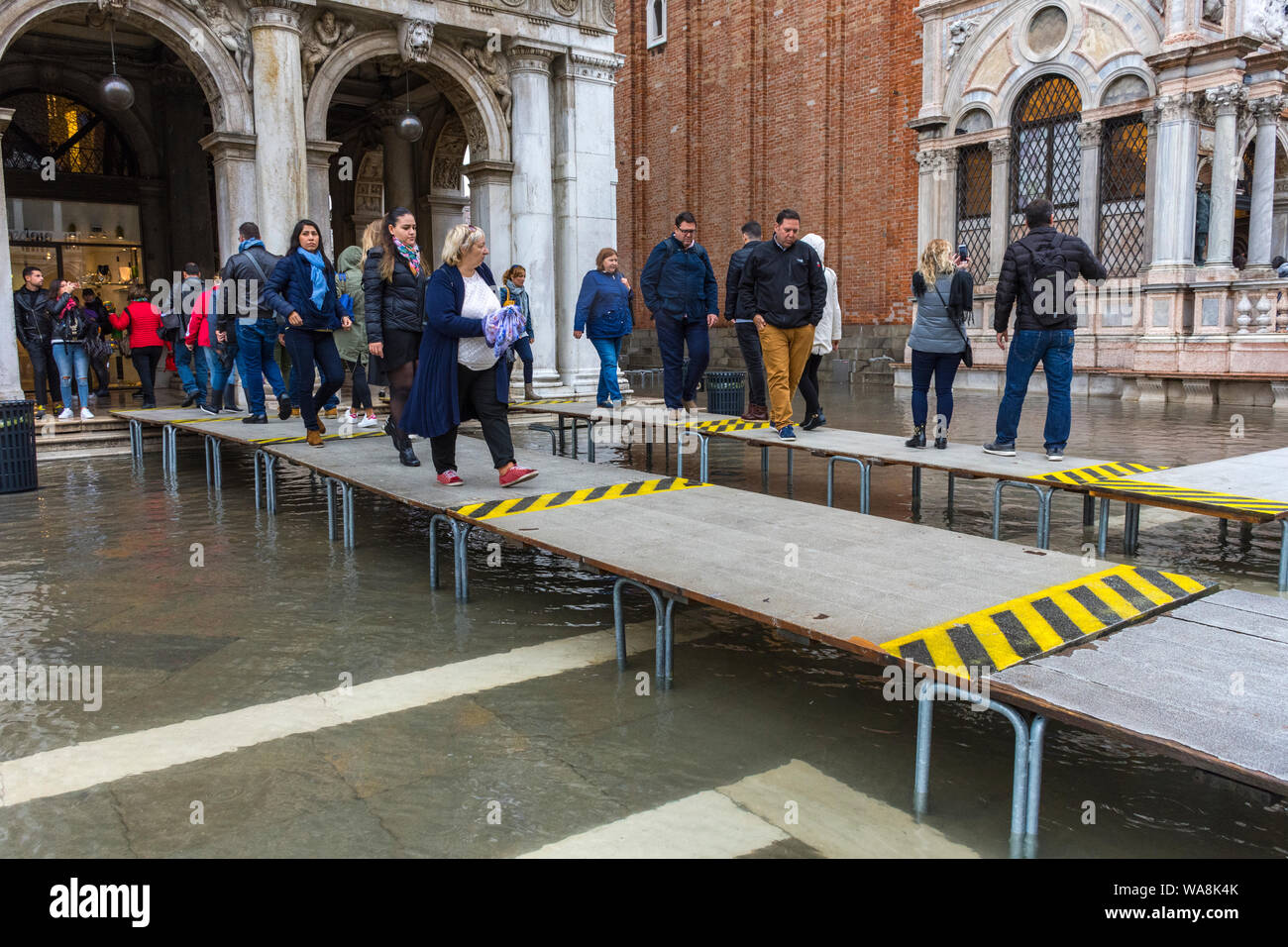 La gente camminare su piattaforme elevate durante un'acqua alta alta (acqua), eventi di Piazza San Marco, Venezia, Italia Foto Stock
