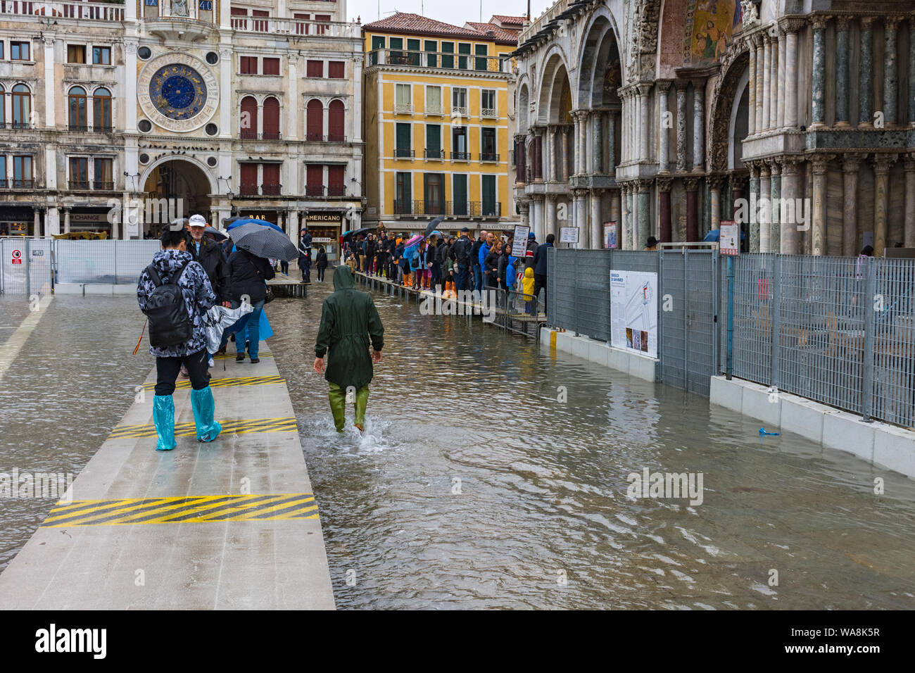 La gente camminare su piattaforme elevate durante un'acqua alta (l'acqua alta) evento, all esterno della Basilica di San Marco, Piazza San Marco, Venezia, Italia Foto Stock