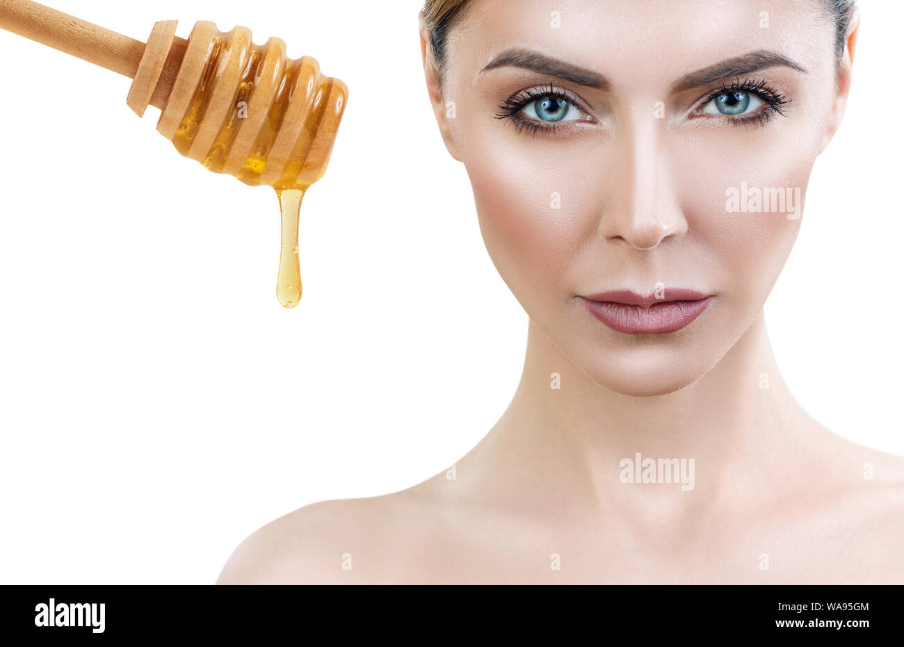 Bella donna vicino a cucchiaio di miele con fluisce giù il miele preparare per il miele maschera facciale. Foto Stock